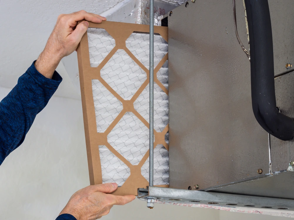 Technician pulls out air filter from HVAC system.