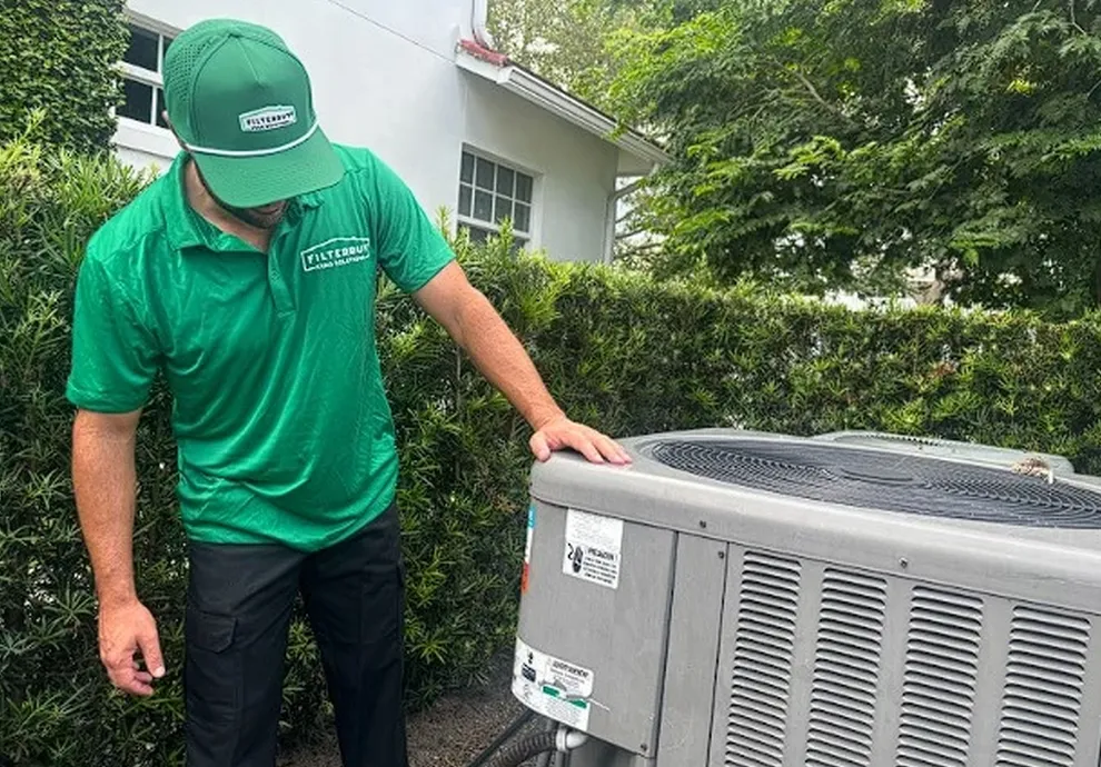 An image of an HVAC technician inspecting an outdoor AC unit, representing HVAC system repair cost and price estimates.