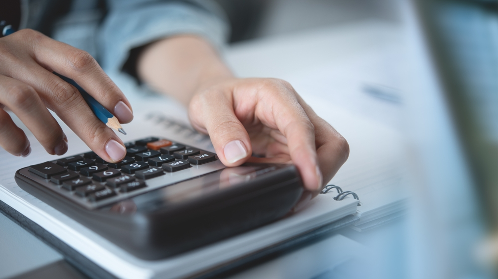 An image of a person using a calculator to estimate the cost of UV light installation.