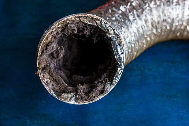 An image of a dryer vent clogged with lint, showing why cleaning the lint trap like pros is important.