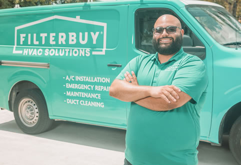 An image of a professional HVAC technician standing confidently in front of a Filterbuy service van, representing the qualities of professional HVAC tuneup specialists.