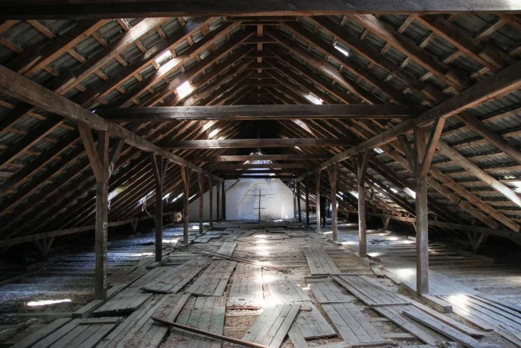 An image of an empty attic with exposed wooden beams and flooring, illustrating the best way to insulate a Florida attic.