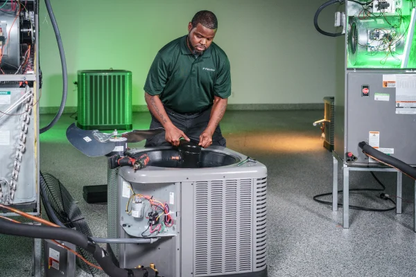 Image of an HVAC technician repairing an outdoor air conditioning condenser unit, representing maintenance and installation costs for a 3-ton AC system.