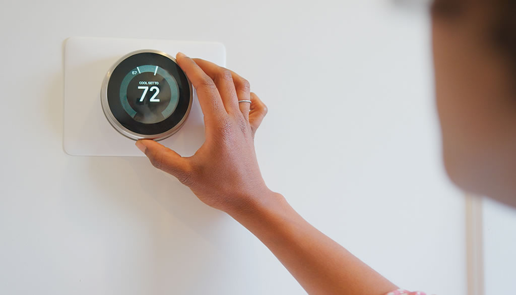 Image of an HVAC technician adjusting smart thermostat set to 72°F, related to understanding EM heat or emergency heat settings from Filterbuy HVAC Solutions.