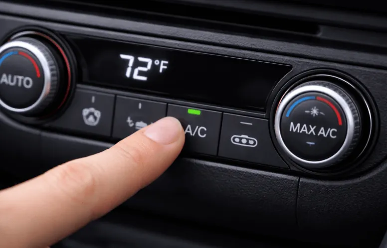 Close-up view of car dashboard climate control set to 72°F with driver pressing A/C button, illustrating car air conditioner repair and replacement cost considerations