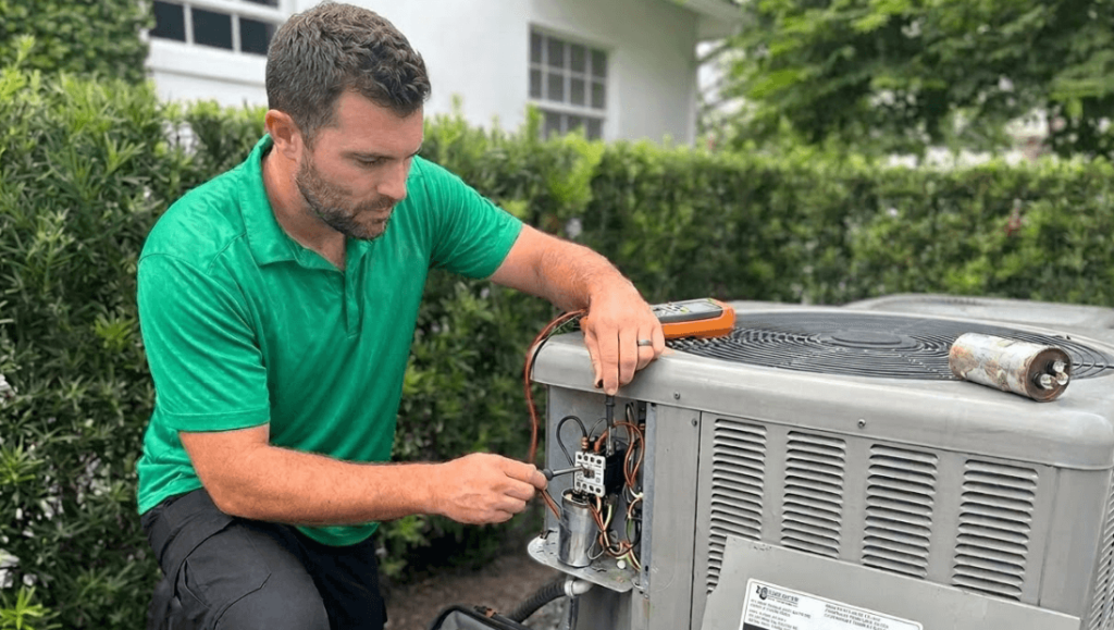 A view of an HVAC technician repairing an outdoor air conditioner condenser unit while performing professional AC repair service at a residential home.